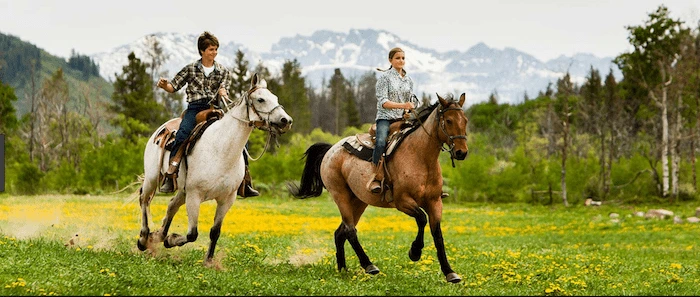 Confident plus-size woman riding Thrapston a horse through a field with a smile on her face.